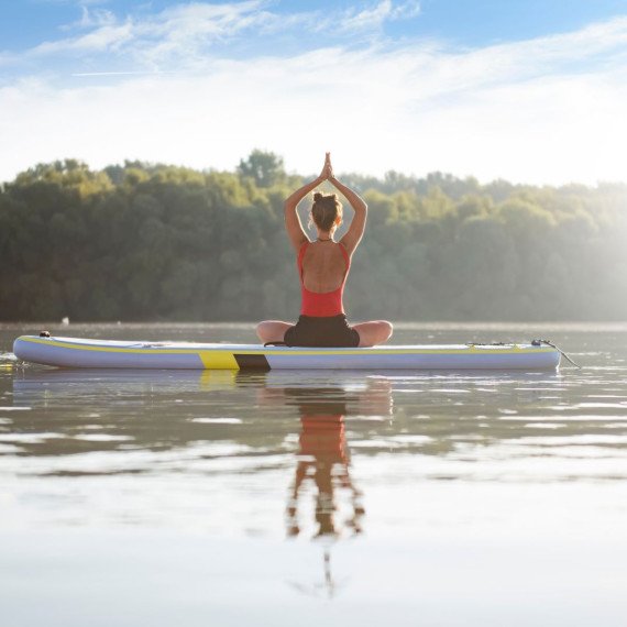 Женщина занимается йогой на SUP-борде на озере в солнечный день