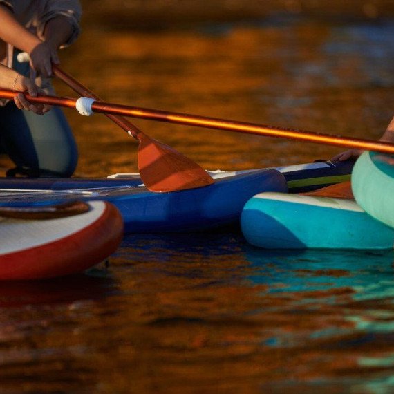 Люди на paddleboard'ах в воде в вечерний час Люди на paddleboard'ах в воде в вечерний час