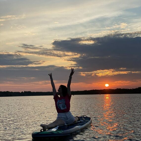 Женщина на каяке радостно встречает закат на водоёме в летний вечер Женщина на каяке радостно встречает закат на водоёме в летний вечер