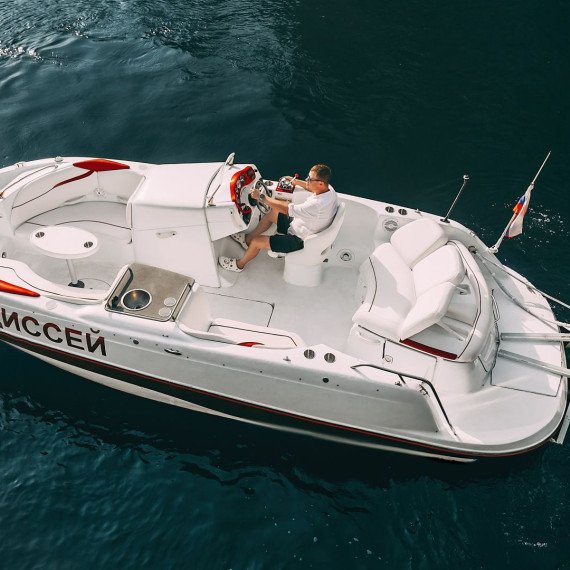 Человек управляет моторной лодкой на воде в ясный день