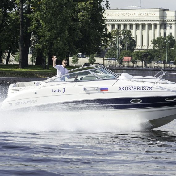 На реке моторная лодка на высокой скорости около здания академии в Москве