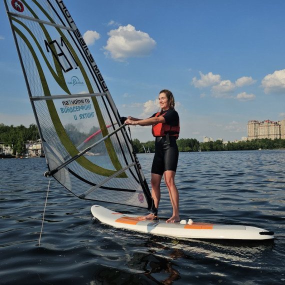 Серфер стоит на доске с парусом на воде в городе в ясный день