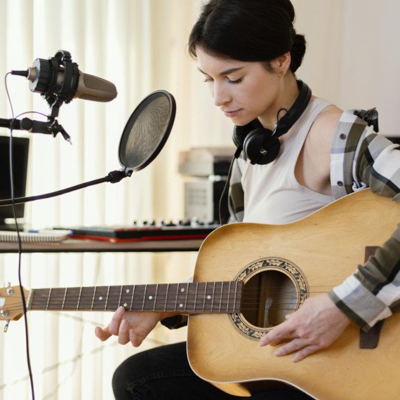 Девушка играет на гитаре в студии звукозаписи Девушка играет на гитаре в студии звукозаписи
