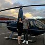 Пара стоит рядом с вертолетом на фоне вечернего неба в аэропорту - превью 1