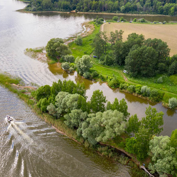 Пейзаж реки с зелеными берегами и лодкой на воде, снятый в солнечный день. Фото 13