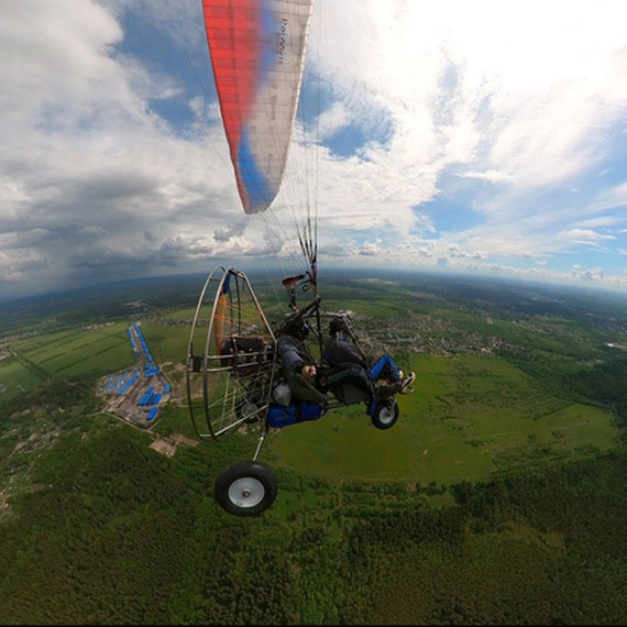 Парапланерный полет над зелеными полями и лесами в ясный день