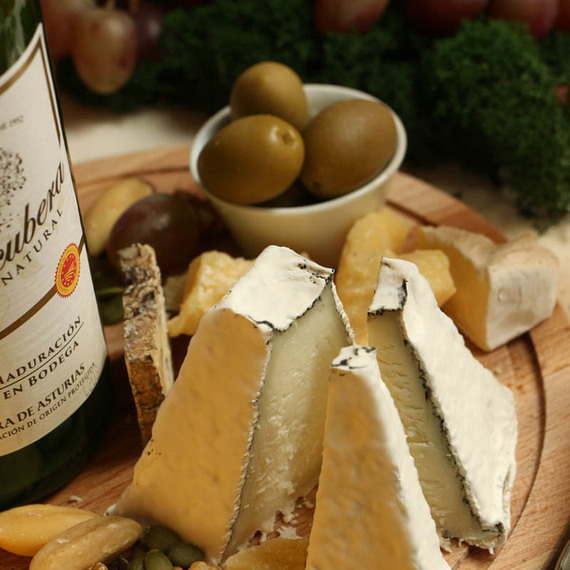 Ассорти из сыра и виноград на деревянной тарелке, окруженное оливками и орехами на столе Ассорти из сыра и виноград на деревянной тарелке, окруженное оливками и орехами на столе