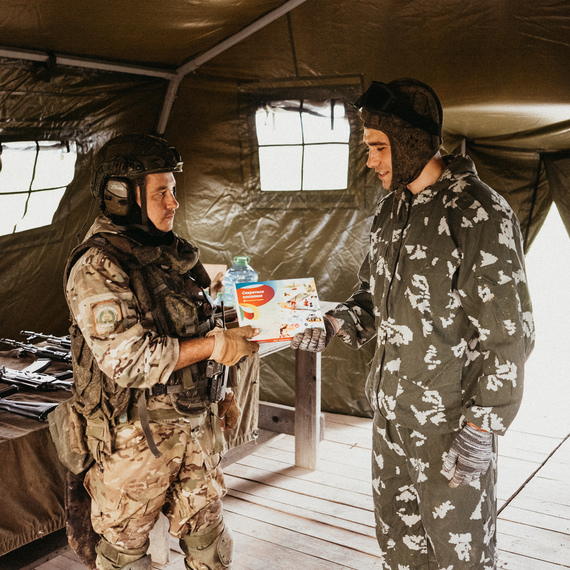 Военные учения на базе, солдат передает награду гражданскому лицу в уютном палаточном лагере. Фото 37