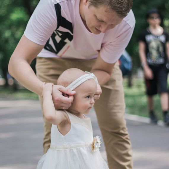 Отец гуляет с дочкой в парке, помогая ей делать первые шаги в солнечный день. Фото 9