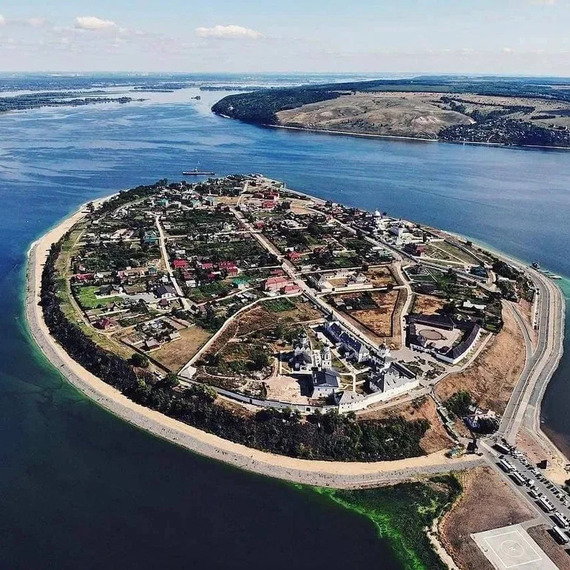 Остров на реке с поселением и зелеными насаждениями, снятый с высоты в ясный солнечный день. Фото 4