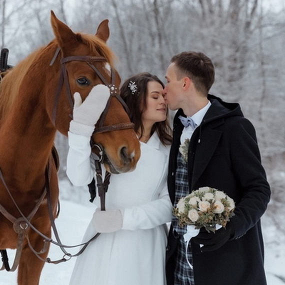 Молодожены на зимней прогулке с лошадью в заснеженном лесу