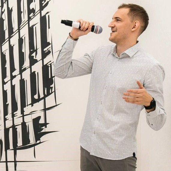 Мужчина с микрофоном говорит на стенде в выставочном центре на мероприятии