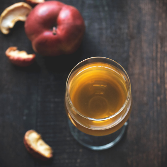 Напиток из яблок на деревянной поверхности с яблоком и коркой рядом