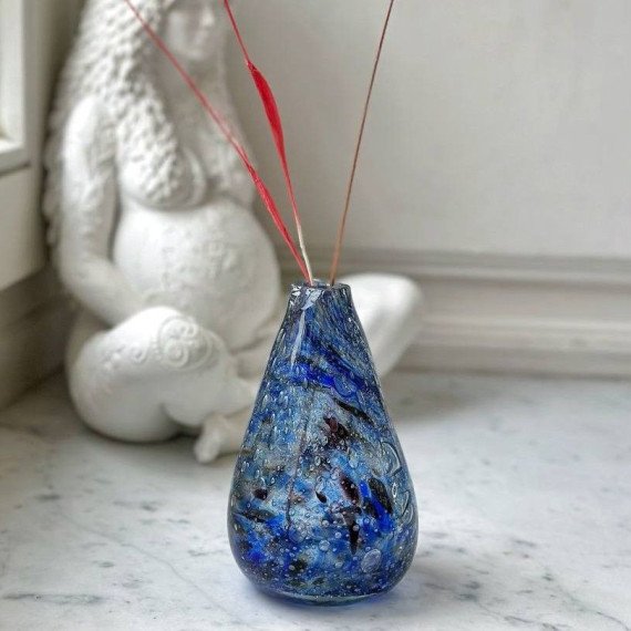 Ваза с синими узорами и палочками аромата на фоне статуи