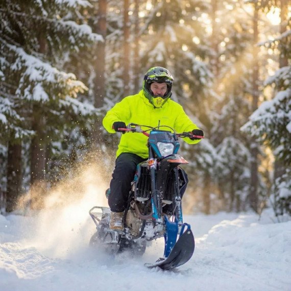 Мужчина катается на снегоходе по снежному лесу в зимний солнечный день. Главное фото
