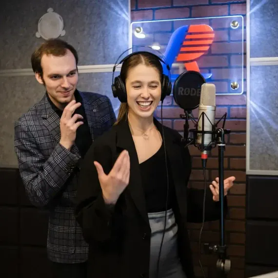 Молодая певица записывает вокал в студии звукозаписи с помощью звукорежиссера. Главное фото