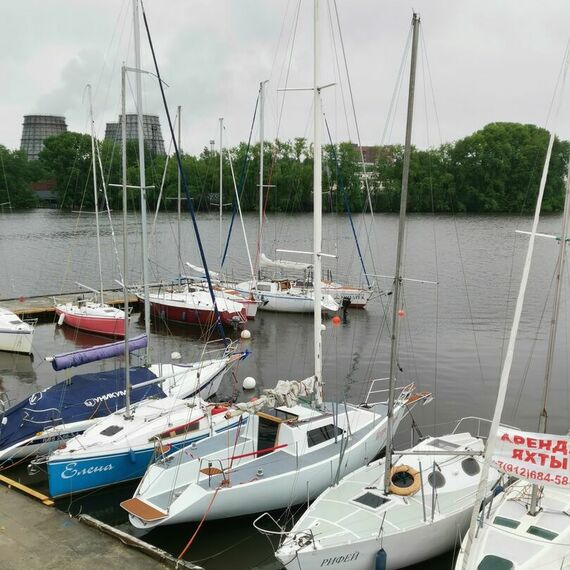 Яхты на стоянке у реки в облачный день, спокойная вода и зелень вокруг. Фото 4