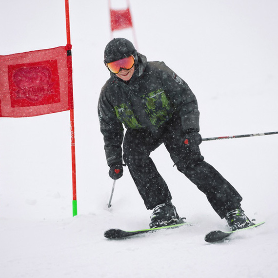 Лыжник проходит сквозь красные ворота на заснеженной горнолыжной трассе в зимний период