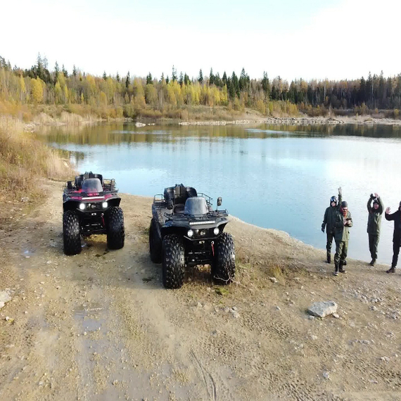 Внедорожные транспортные средства рядом с водоемом в лесистой местности в осеннее время