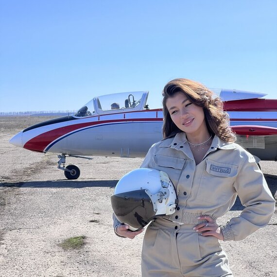 Женщина-пилот позирует рядом с самолетом на аэродроме в солнечный день. Главное фото