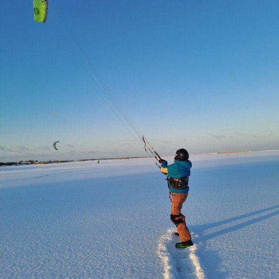 Ледяное побережье, кайтсерфер управляет кайтом в ясный зимний день на открытом пространстве