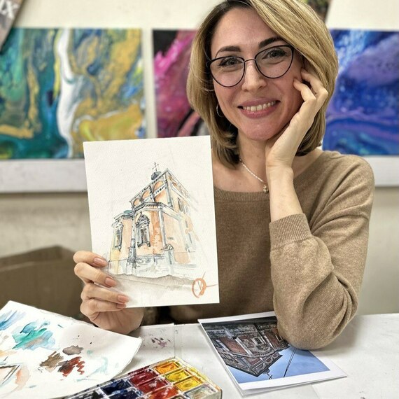 Женщина с акварельным рисунком здания в студии уютного художественного класса в Москве на протяжении зимнего дня. Фото 9