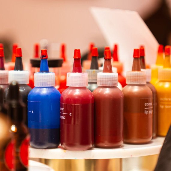 Разноцветные бутылочки с красками для макияжа на столе в косметическом магазине