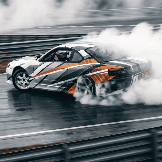 Дрифтующий автомобиль на гоночной трассе в дождливую погоду. Главное фото