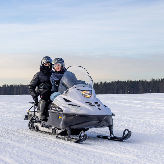 Люди катятся на снегоходе по зимнему ландшафту в ясный день