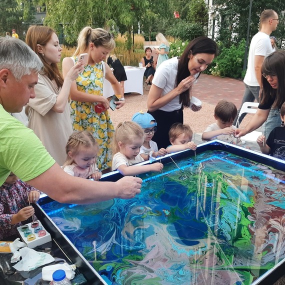 Дети и взрослые создают абстрактные рисунки с помощью цветного мыла в парке во время летнего мастер-класса. Фото 6