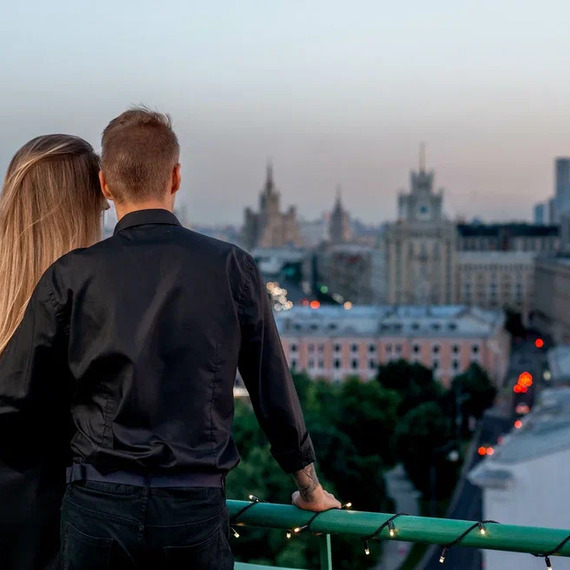 Пара наслаждается закатом над Москвой с высоты здания, смотря на величественные городские пейзажи и огни. Фото 6