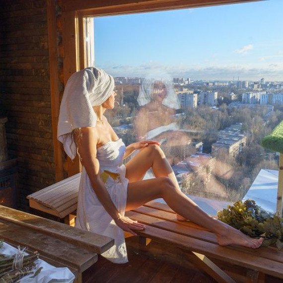 Женщина смотрит в окно с сауны, вид на город. Главное фото