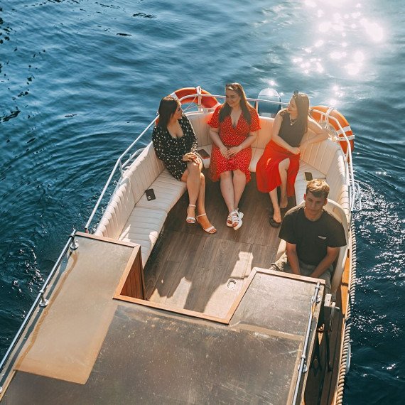 Четыре человека отдыхают на лодке в солнечный день на воде