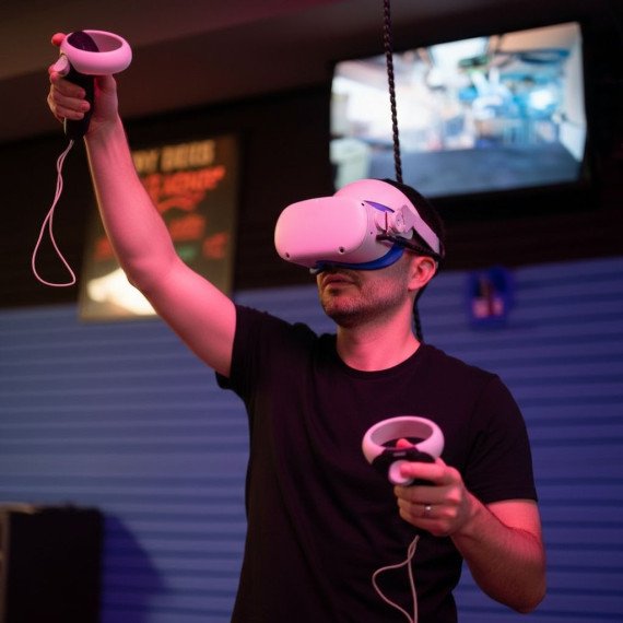 Мужчина играет в виртуальной реальности с контроллерами в игровом зале Мужчина играет в виртуальной реальности с контроллерами в игровом зале