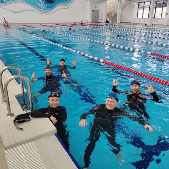 Группа людей плавает в бассейне в спортивном комплексе в светлое время дня