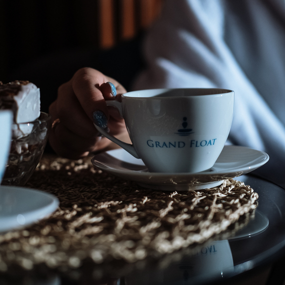 Человек держит чашку кофе Grand Float в уютном интерьере с мягким освещением и сладкой закуской в вечернее время. Фото 4