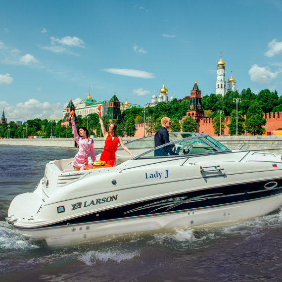На реке в Москве три человека на лодке рядом с Кремлём