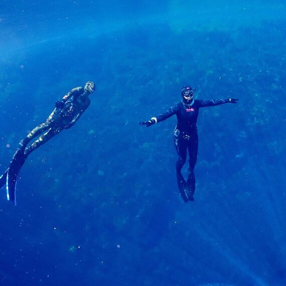 Два дайвера плавают под водой в открытом морском пространстве среди кораллового рифа