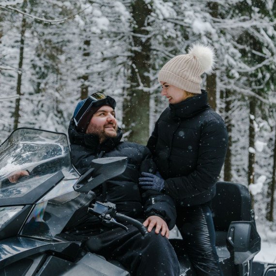Мужчина и женщина катаются на снегоходе в снежном лесу зимой