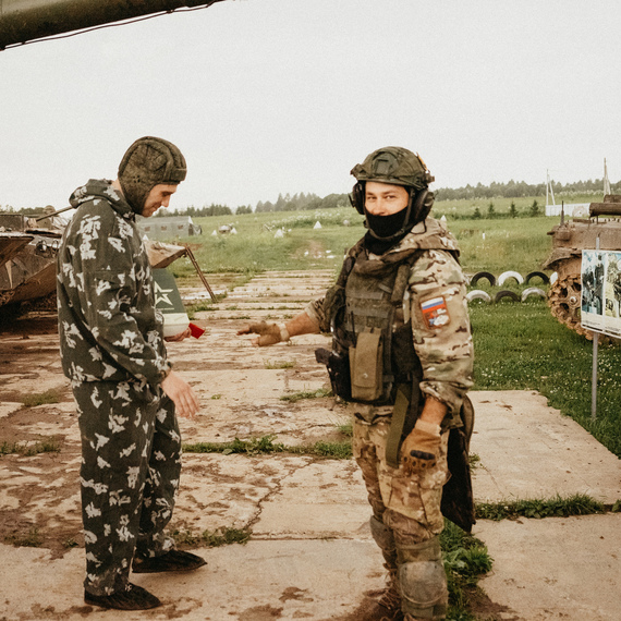 На военной базе два человека обсуждают детали военной техники на фоне танков. Фото 24