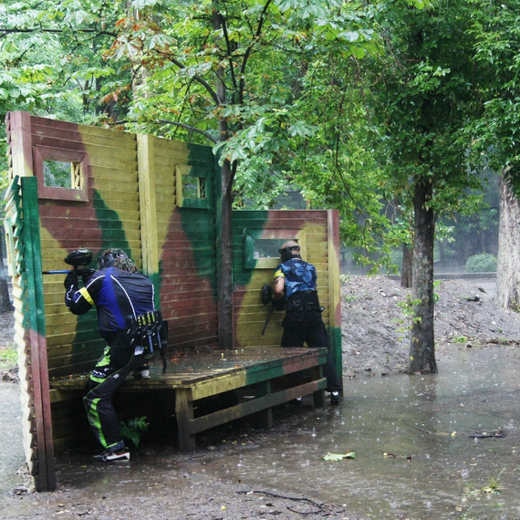 Два игрока в пейнтбол прячутся за укрытием во время сильного дождя в лесу. Фото 11