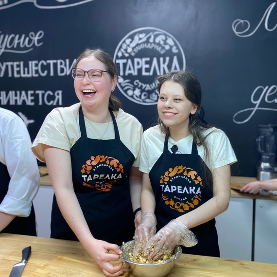 Две девушки готовят в кулинарной мастерской, наполняя тарелку вкусной смесью во время урока по приготовлению блюд. Фото 6