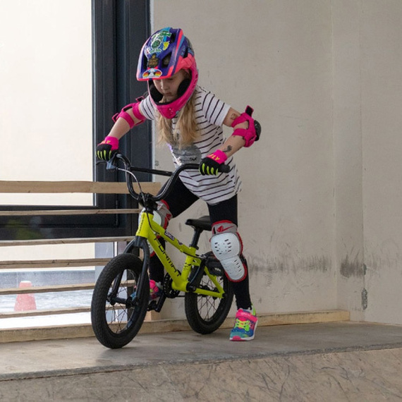 Девочка катается на BMX на рампе в закрытом скейтпарке в утреннее время, одетая в защитную экипировку. Фото 20