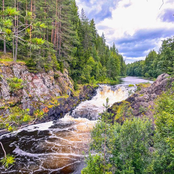Красивый водопад на реке, окружённый зелёным лесом и скалами в летний день. Главное фото