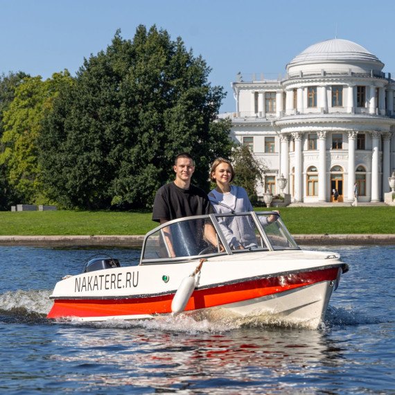 Молодые люди на лодке катаются по реке рядом с историческим зданием в ясный день