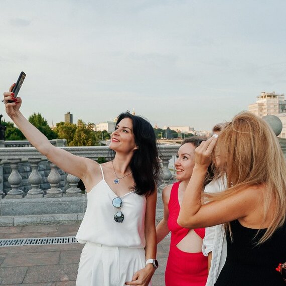 Группа женщин делает селфи на мосту в Москве в летний вечер