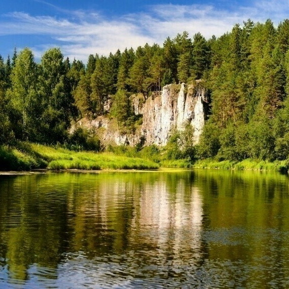 Укромный уголок природы у реки с зелеными берегами и скалистыми обрывами в ясный летний день