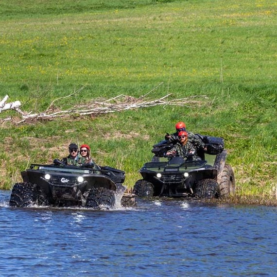 Два квадроцикла пересекают воду у берега реки на фоне зеленых лугов и деревьев в солнечный день. Фото 12