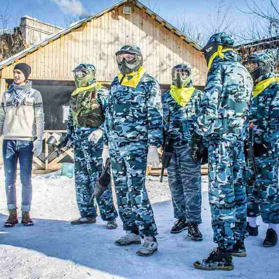 Группа людей в зимней камуфляжной одежде на фоне деревенского дома во время активного отдыха на снегу. Фото 5