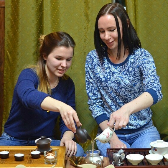 Две женщины готовят чай в уютной чайной комнате с зеленым покрытием стен, погружаясь в традиционный ритуал чаепития. Фото 10